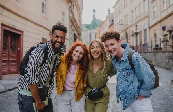 A front view of group of happy young people outdoors on trip in town, looking at camera.