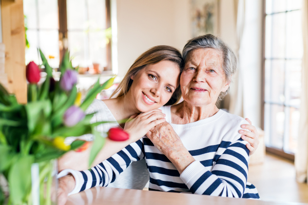 Portrait of an elderly grandmother with an adult granddaughter at home.