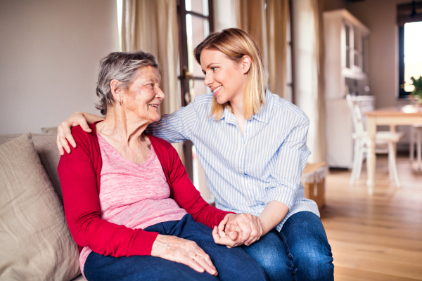 Portrait of an elderly grandmother with an adult granddaughter sitting on the sofa at home. Close up.