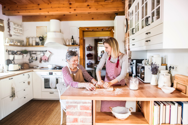 A happy elderly grandmother with an adult granddaughter at home, baking.