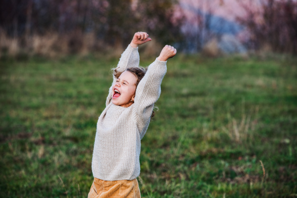 Side view of cheerful small girl running in autumn nature. Copy space.