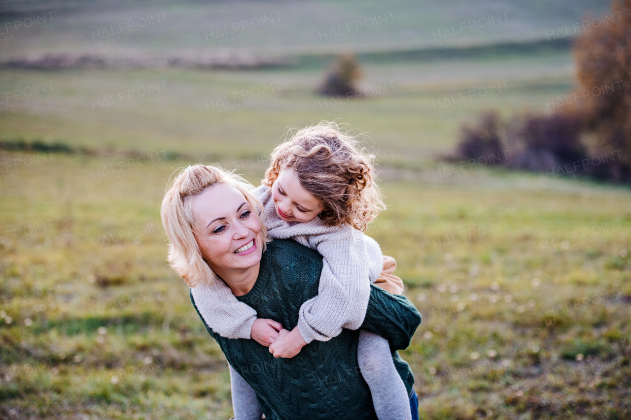 Portrait of small girl with mother on a walk in autumn nature, having fun.