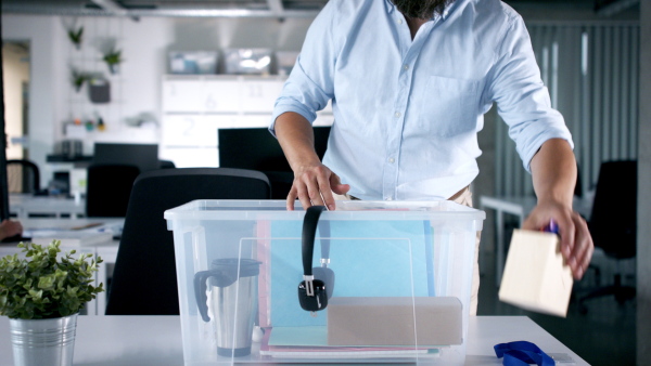 Unrecognizable man cleaning desk indoors in office, loosing job due to coronavirus.