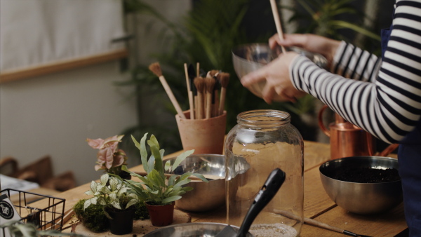 Midsection of unrecognizable woman florist in flower and plant shop, making terrarium.