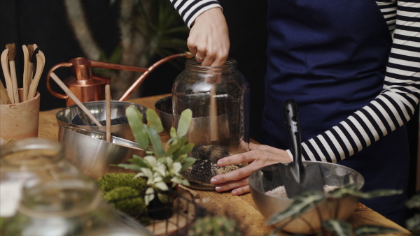 Midsection of unrecognizable woman florist in flower and plant shop, making terrarium.