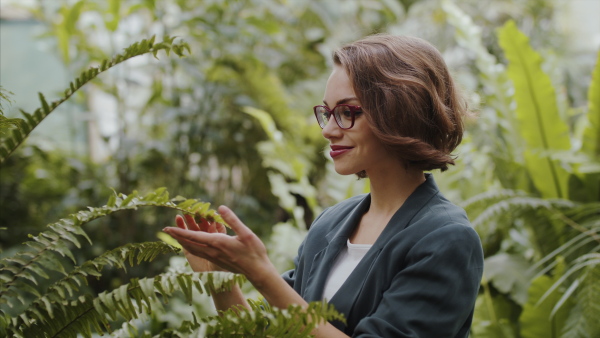 A female researcher standing in botanical garden, exploring plants.