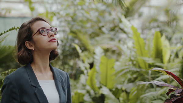 A female researcher standing in botanical garden, exploring plants.