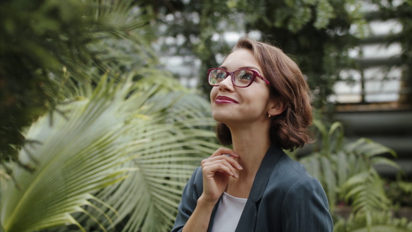 A female researcher standing in botanical garden, exploring plants.