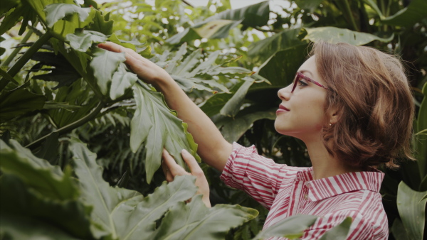 A female researcher standing in botanical garden, exploring plants.