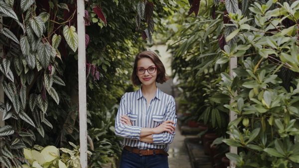 Beautiful young woman standing in botanical garden, looking at camera.