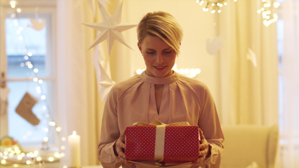 Portrait of young woman with present indoors at home at Christmas, looking at camera.