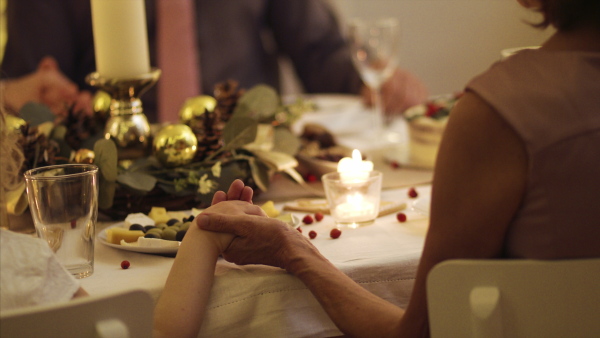 Close-up of hands holding together at the table at Christmas, detail. Praying concept.