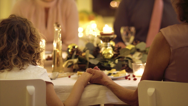 Extended family holding hands together at the table at Christmas, praying concept.