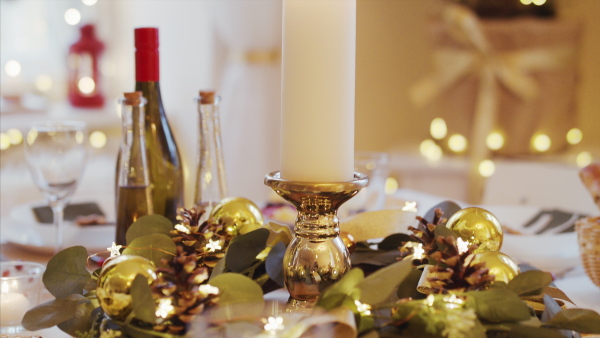 A close-up of candle on table set for dinner meal at Christmas time.