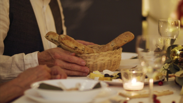 Midsection of unrecognizable senior couple indoors at home sitting at the table at Christmas, eating.