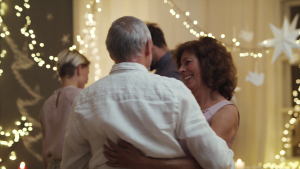 Happy multi-generation family indoors celebrating Christmas together, dancing.