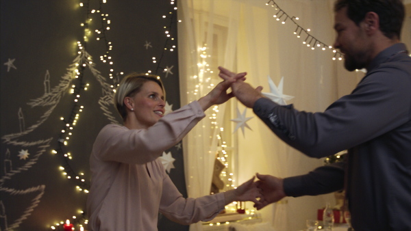 Portrait of cheerful mature couple in love indoors at home at Christmas, dancing.