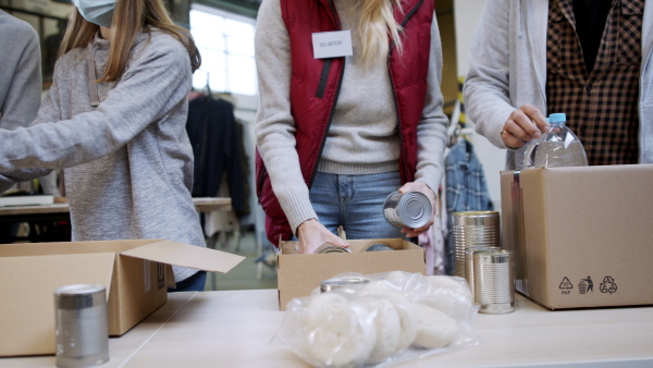 Group of volunteers working in community charity donation center, food bank and coronavirus concept.