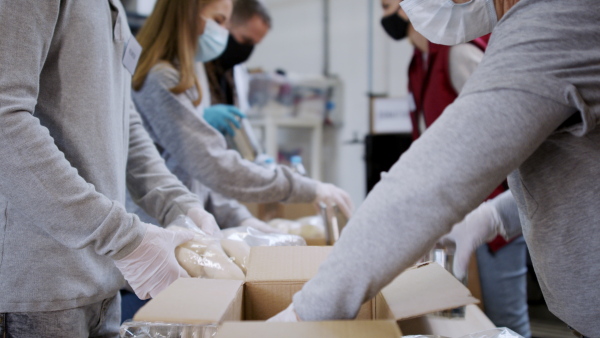 Group of volunteers working in community charity donation center, food bank and coronavirus concept.