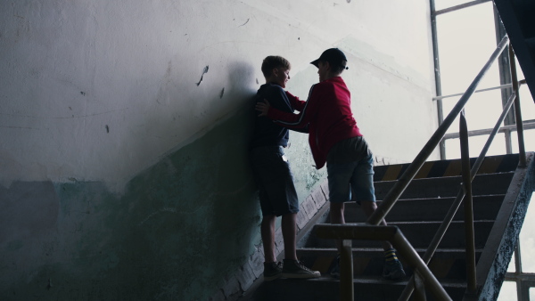 Teenage boy attacked by thug indoors in abandoned building, gang violence and bullying concept.