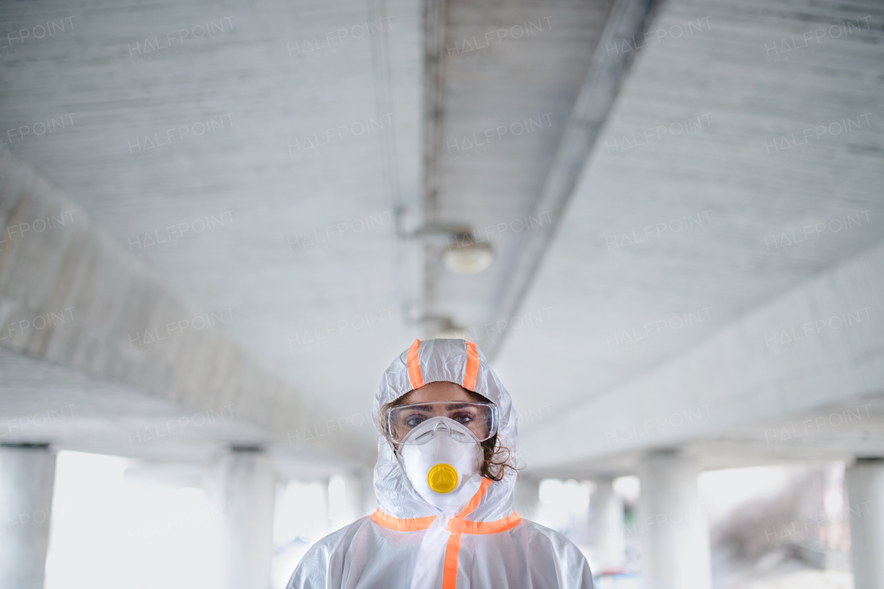 Woman with protective suit and respirator standing outdoors, coronavirus concept. Copy space.