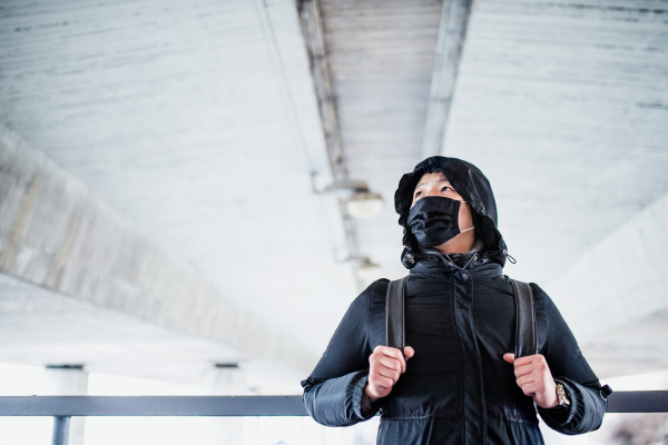 Man in black clothes and respirator standing outdoors in city, coronavirus concept. Copy space.