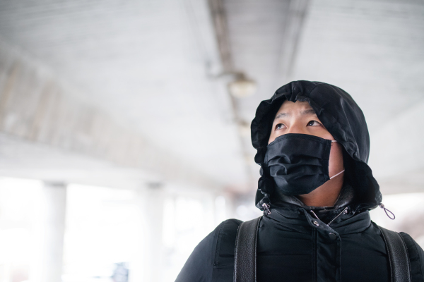 Man in black clothes and mask standing outdoors in city, coronavirus concept. Copy space.