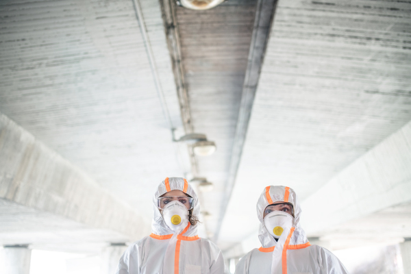 People with protective suits and mask respirators standing outdoors, coronavirus concept.