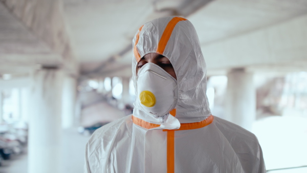 Man with protective suit and respirator standing outdoors, coronavirus concept. Copy space.