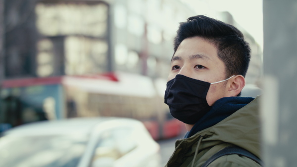 Man with face mask standing on street in city, coronavirus prevention and protection concept.