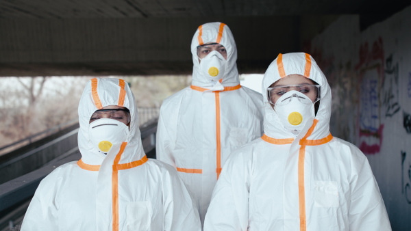 Doctors with protective suits and mask respirators outdoors, coronavirus concept.