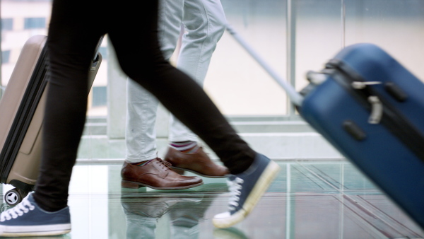 Midsection of legs of people with luggage at the airpot, walking. Holiday concept.