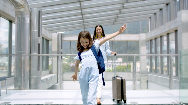 Young mother with daughter going on holiday, wearing face masks at the airport.