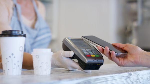 Woman serving coffee through window after quarantine, contactless payment and back to normal concept.