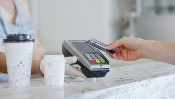 Midsection of unrecognizable woman serving coffee, contactless payment and back to normal concept.