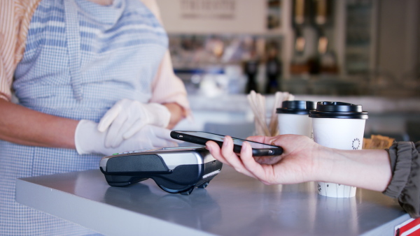 Woman serving coffee after quarantine, contactless payment and back to normal concept.