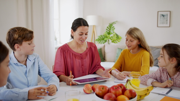 Group of homeschooling children with parent teacher studying indoors, coronavirus concept.