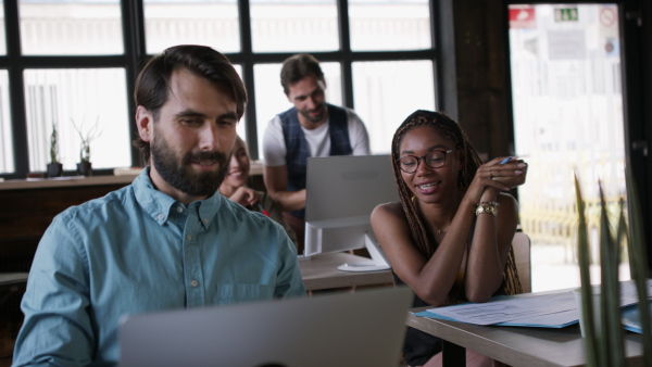 Portrait of group of young businesspeople working indoors in office, discussing issues.