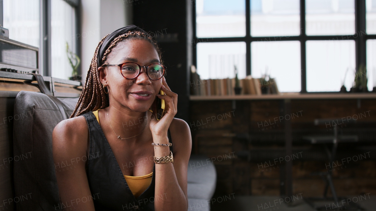 Portrait of young african-american businesswoman indoors in office, using smartphone.