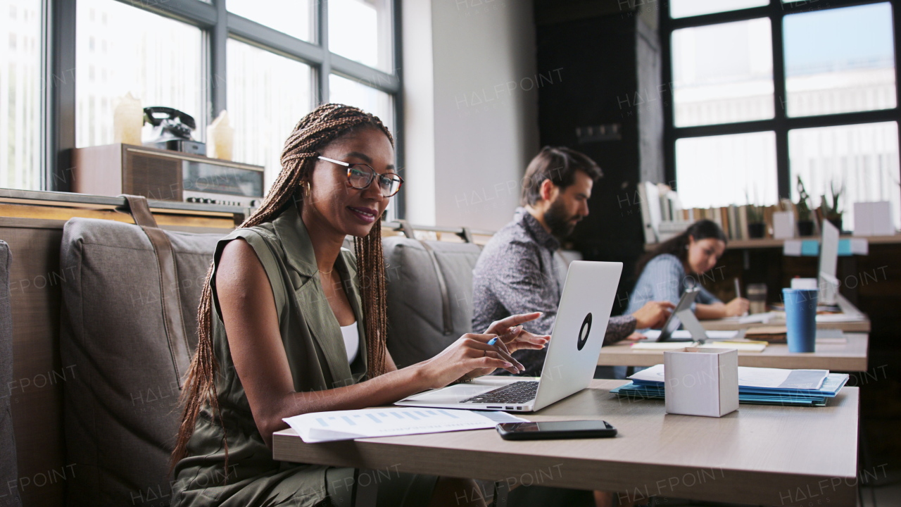 Portrait of group of young businesspeople with laptop sitting and working indoors in office.