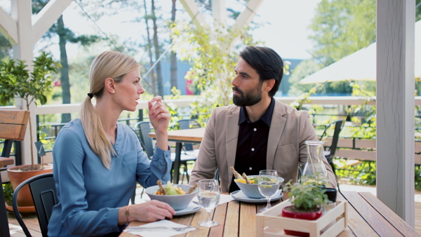 Man and woman business partners sitting outdoors on terrace restaurant, discusssing issues.