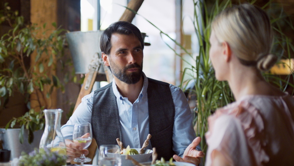 Happy couple sitting indoors in restaurant, talking when having lunch.