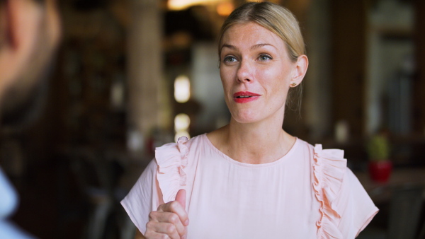 Woman talking to unrecognizable man indoors in restaurant when having lunch.