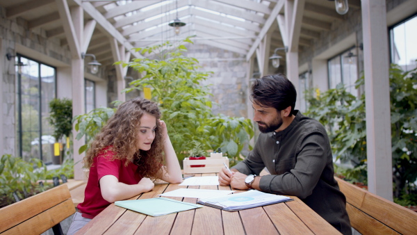 Side view of young man and woman working indoors in office, discussing issues.