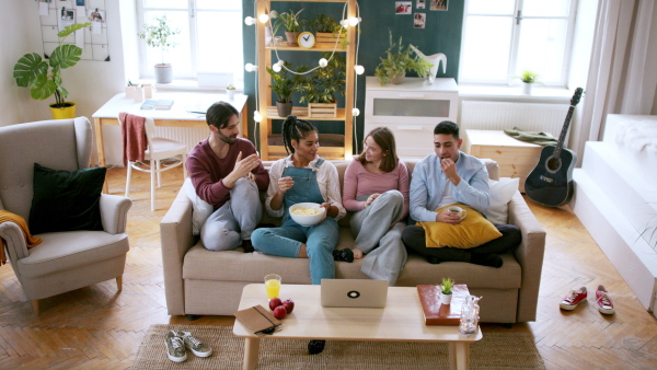 A group of young flatmates sitting on sofa, watching movie, and getting upset house sharing concept.