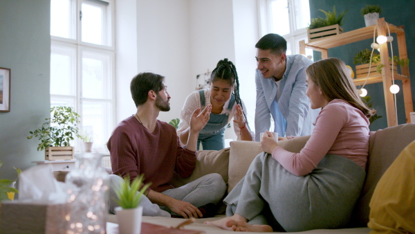 Young friends sitting on sofa and having a funny conversation, house sharing concept.