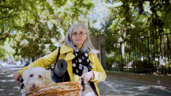 Woman with dog and bicycle standing outdoors in city, looking at camera.