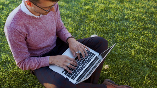 A top view of young businessman working outdoors in city, using laptop.