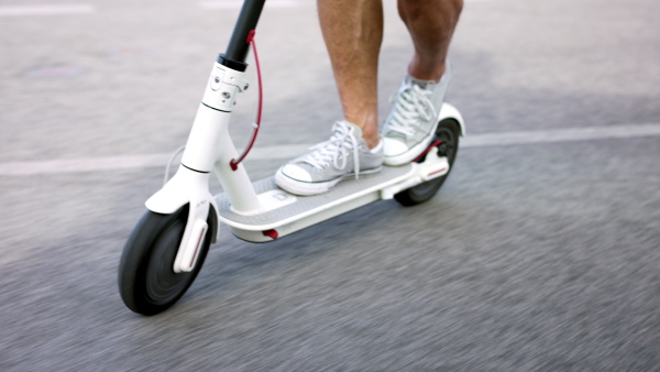 Midsection of unrecognizable commuter riding electric scooter outdoors in city, ecologic transport concept.