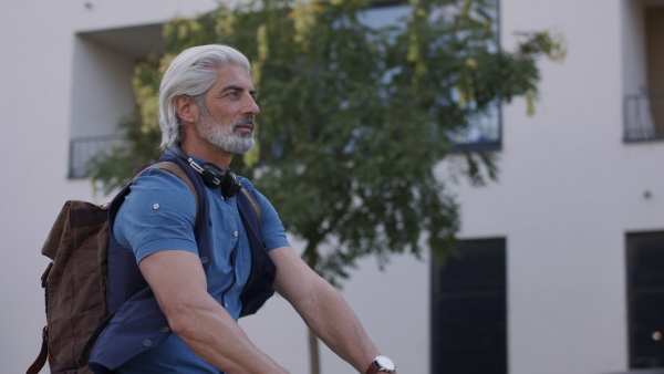 Side view of mature man commuter with electric scooter outdoors in city, going to work.